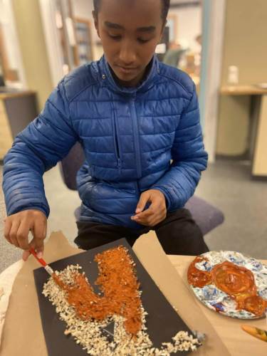 Adam fra 8.trinn maler på sagspon.